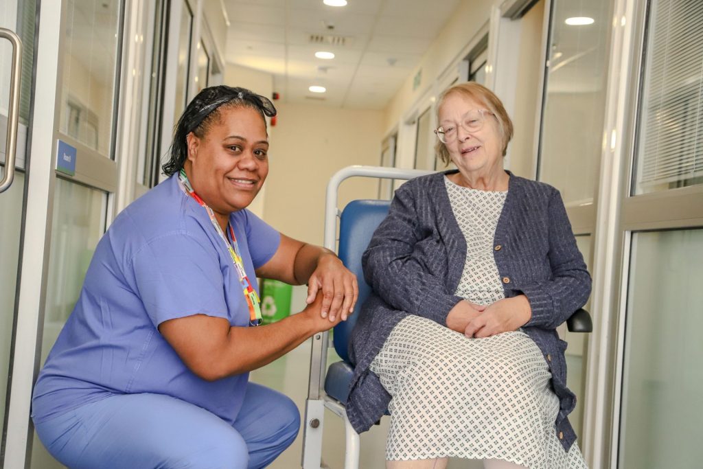 A Theatre Assistant Practitioner chats with a patient sitting in a wheelchair
